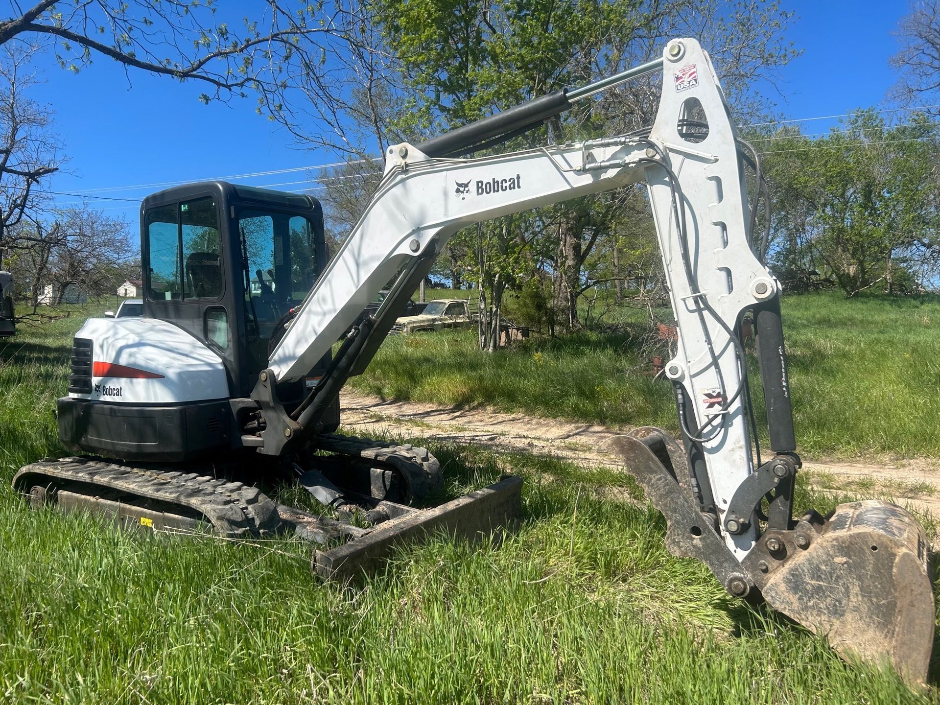 A small excavator is parked in a grassy field.