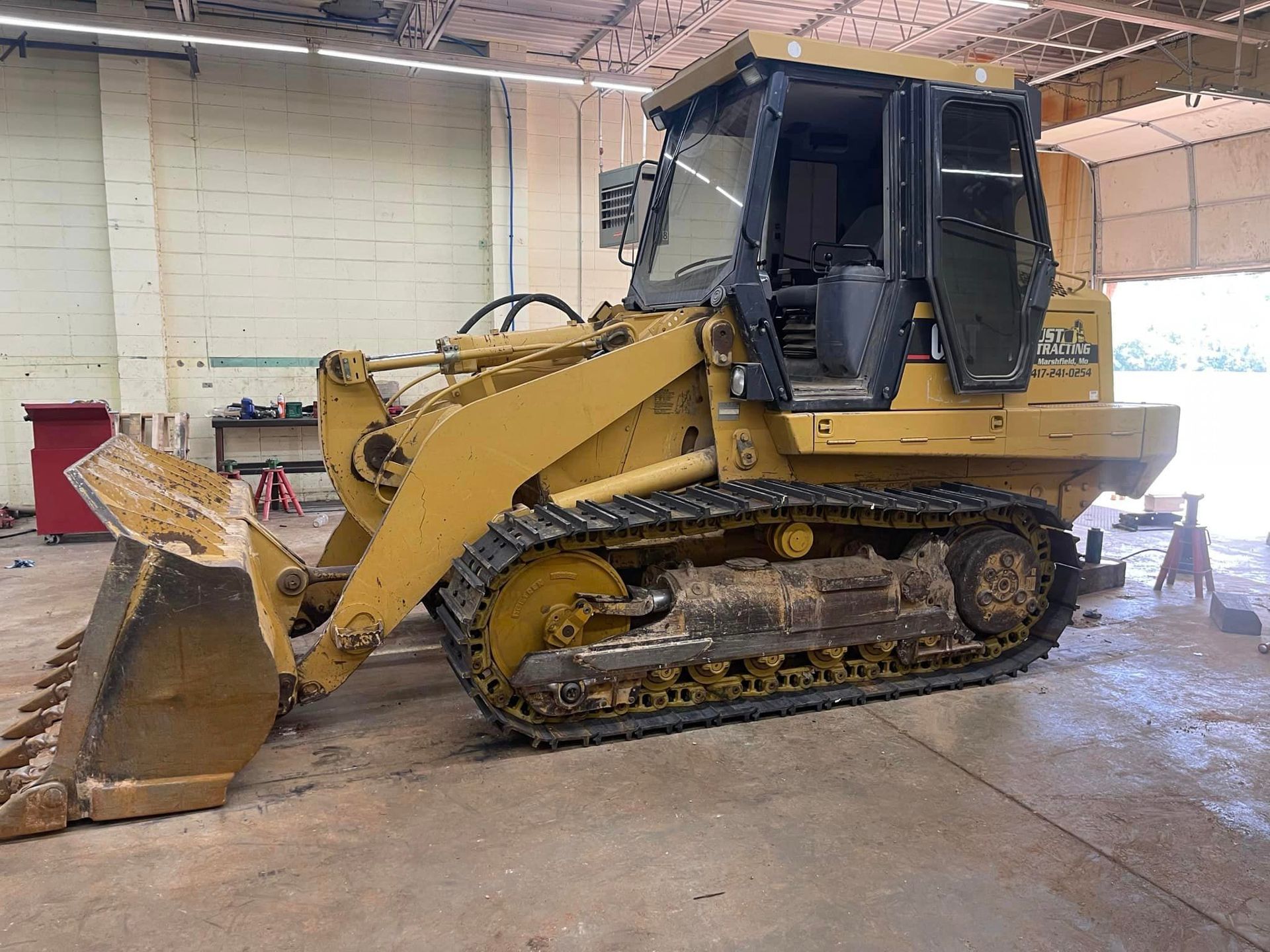 A yellow bulldozer is parked in a garage.