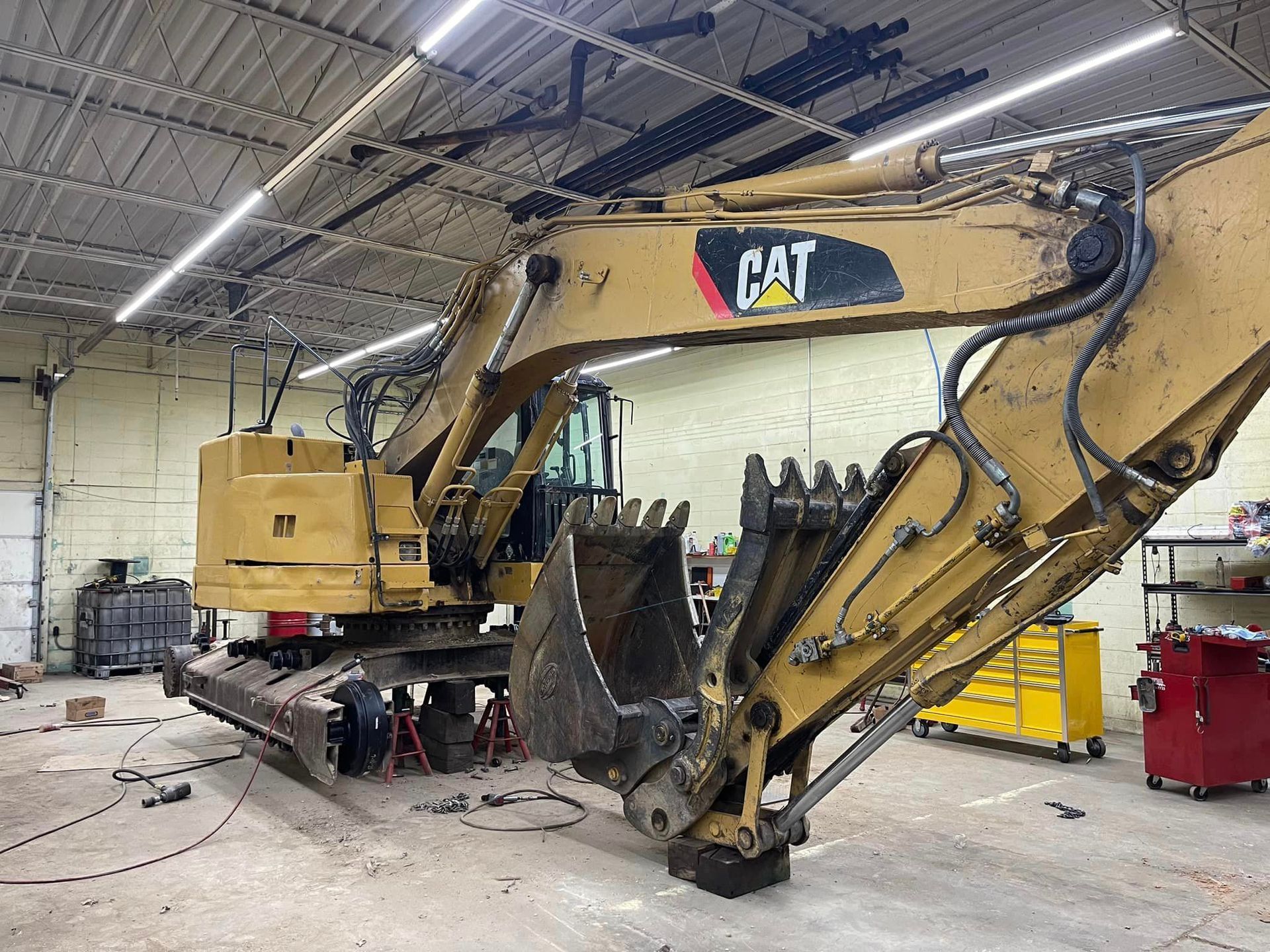 A cat excavator is sitting in a garage.