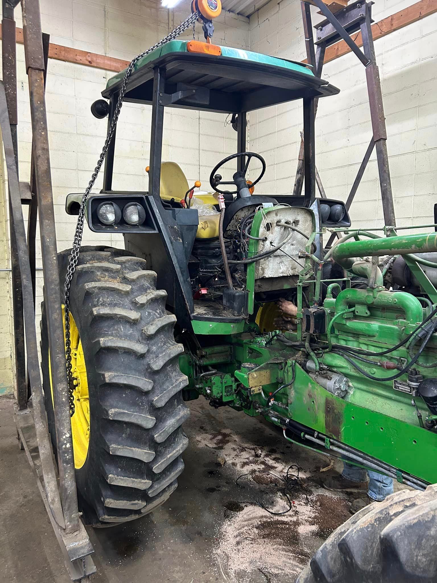 A green and yellow tractor is sitting in a garage.