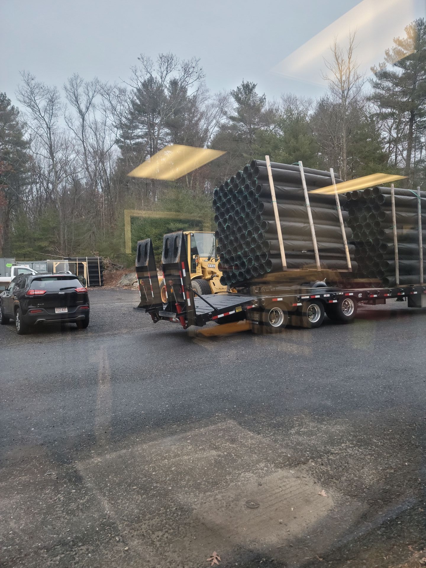 A truck is carrying a stack of pipes on a trailer.