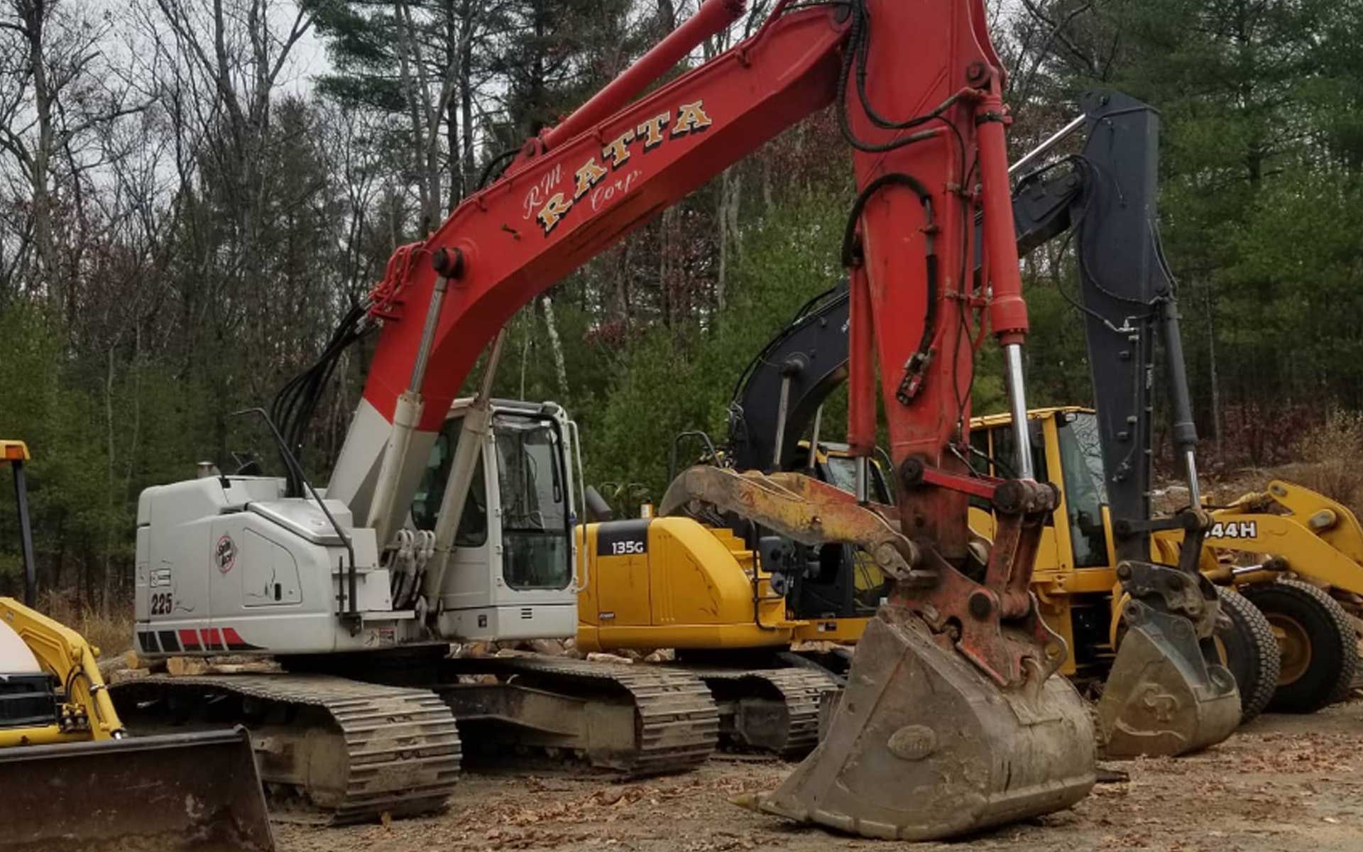 A red and white excavator is parked next to a yellow excavator.
