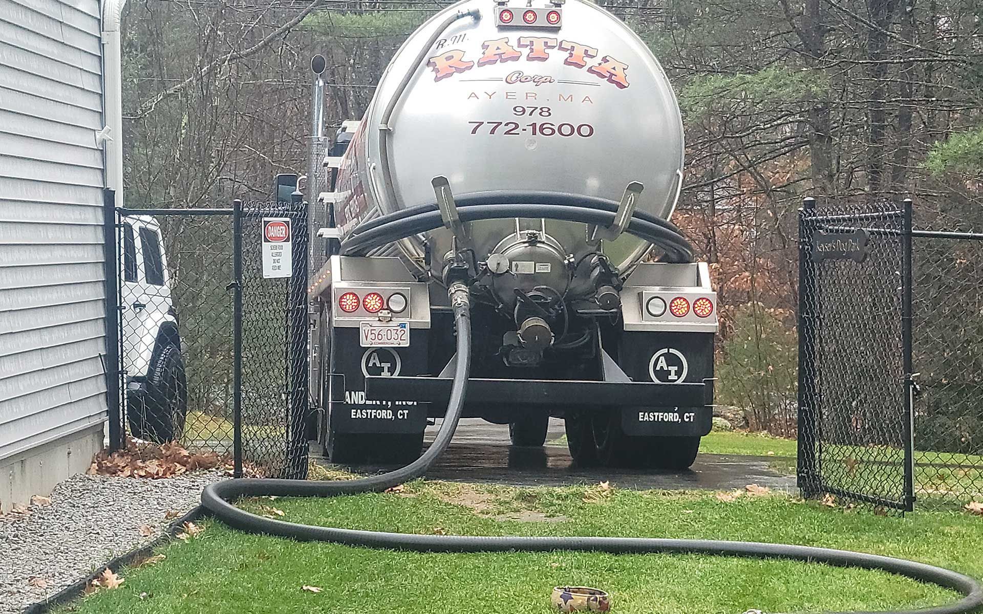 A tanker truck is being filled with water by a hose.