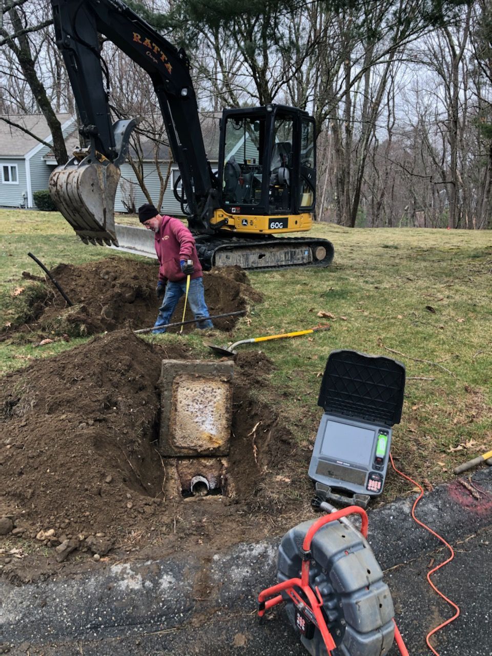 A man is digging a hole in the ground next to an excavator.
