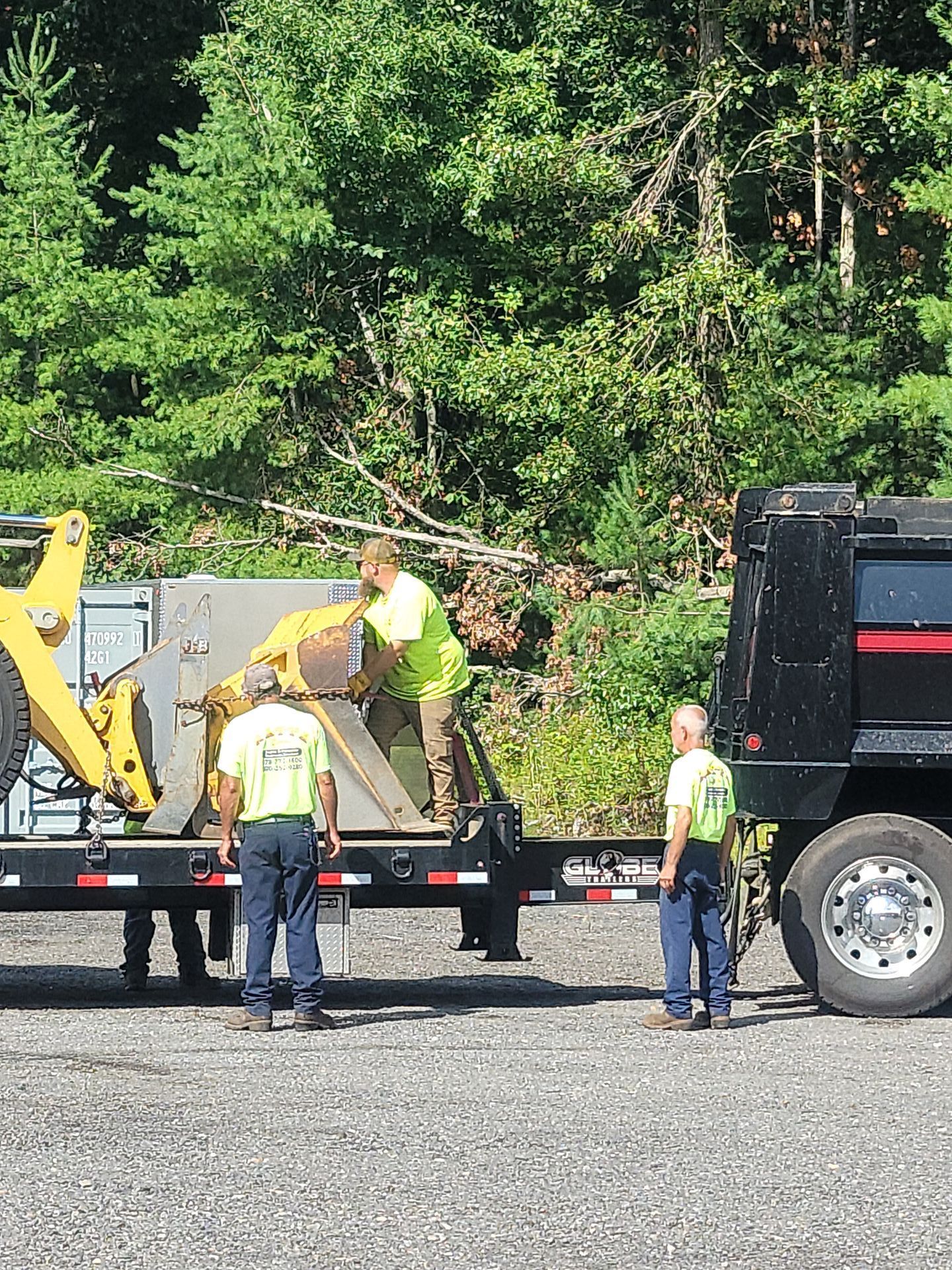 A group of men are standing next to a truck with a bulldozer on it.