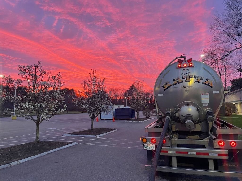A tanker truck is parked in a parking lot at sunset.
