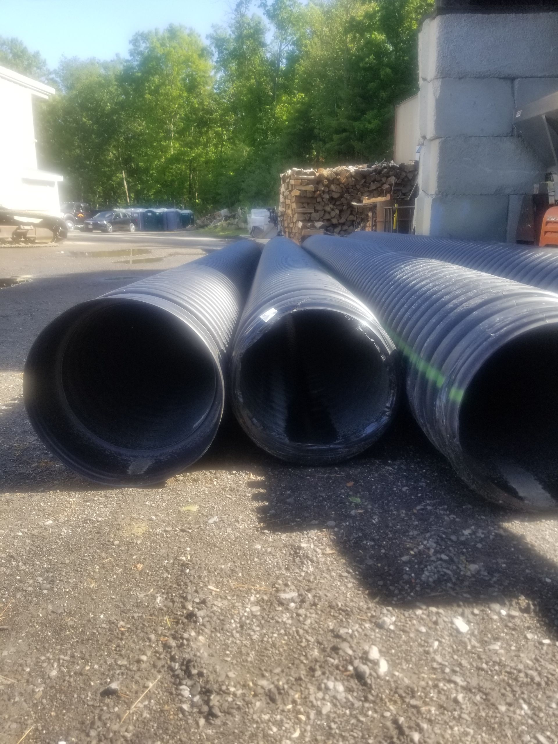 Three black pipes are stacked on top of each other on the ground.