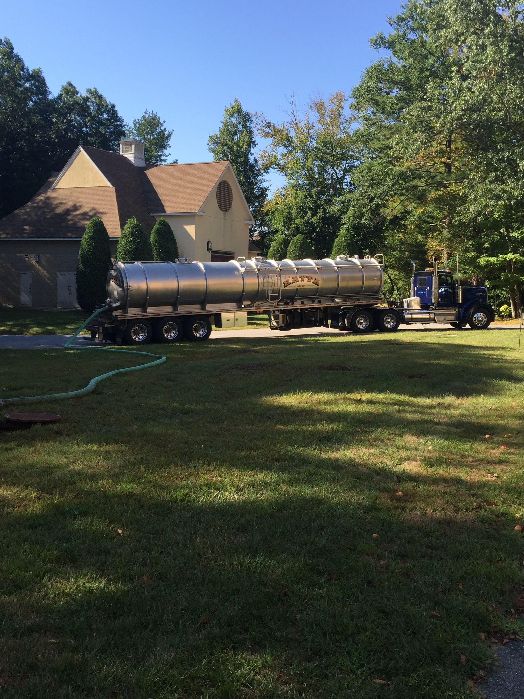 A large tanker truck is parked in front of a house