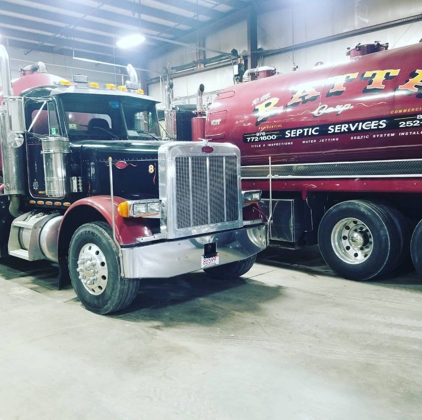 A septic services truck is parked next to another truck in a garage.