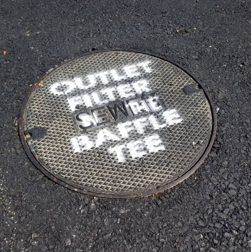 A manhole cover that says outlet filter sewer baffle tee