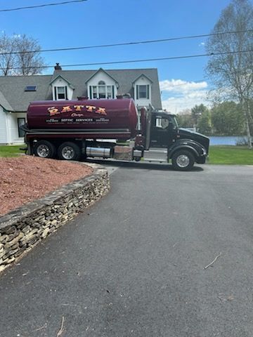 A septic tank truck is parked in front of a house.