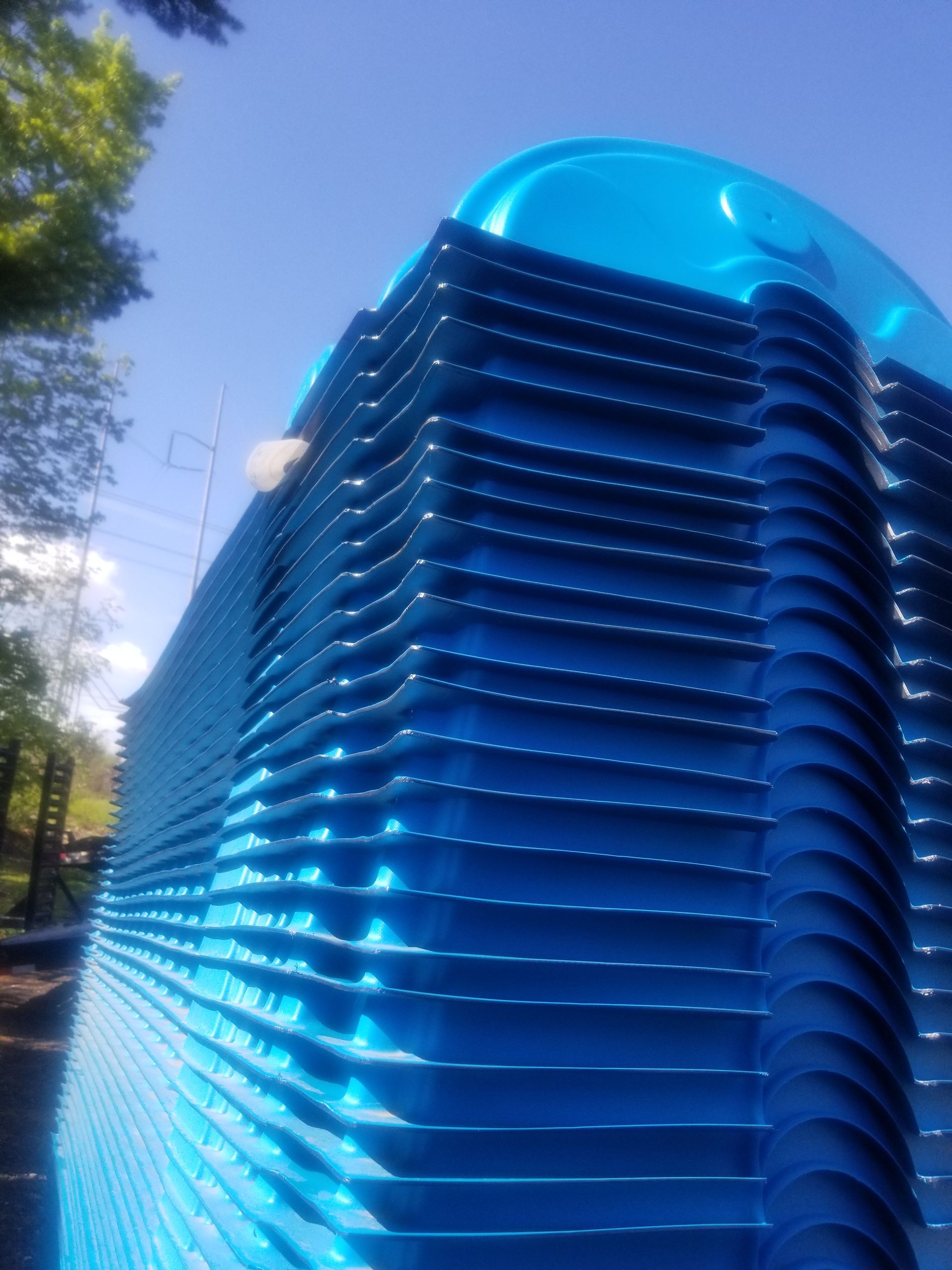 Stack of blue plastic trays outdoors against a blue sky.