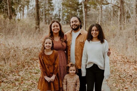 A family is posing for a picture in the woods