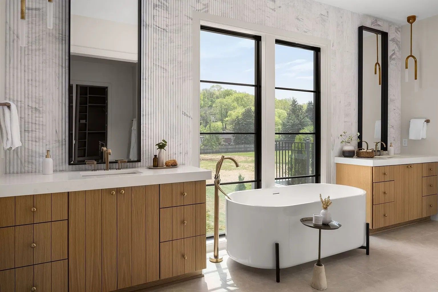 A bathroom with two sinks, a tub, and two mirrors.