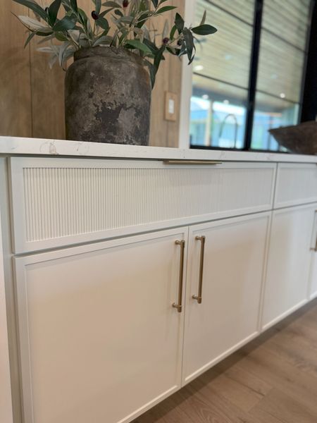 A white cabinet with a vase of flowers on top of it.