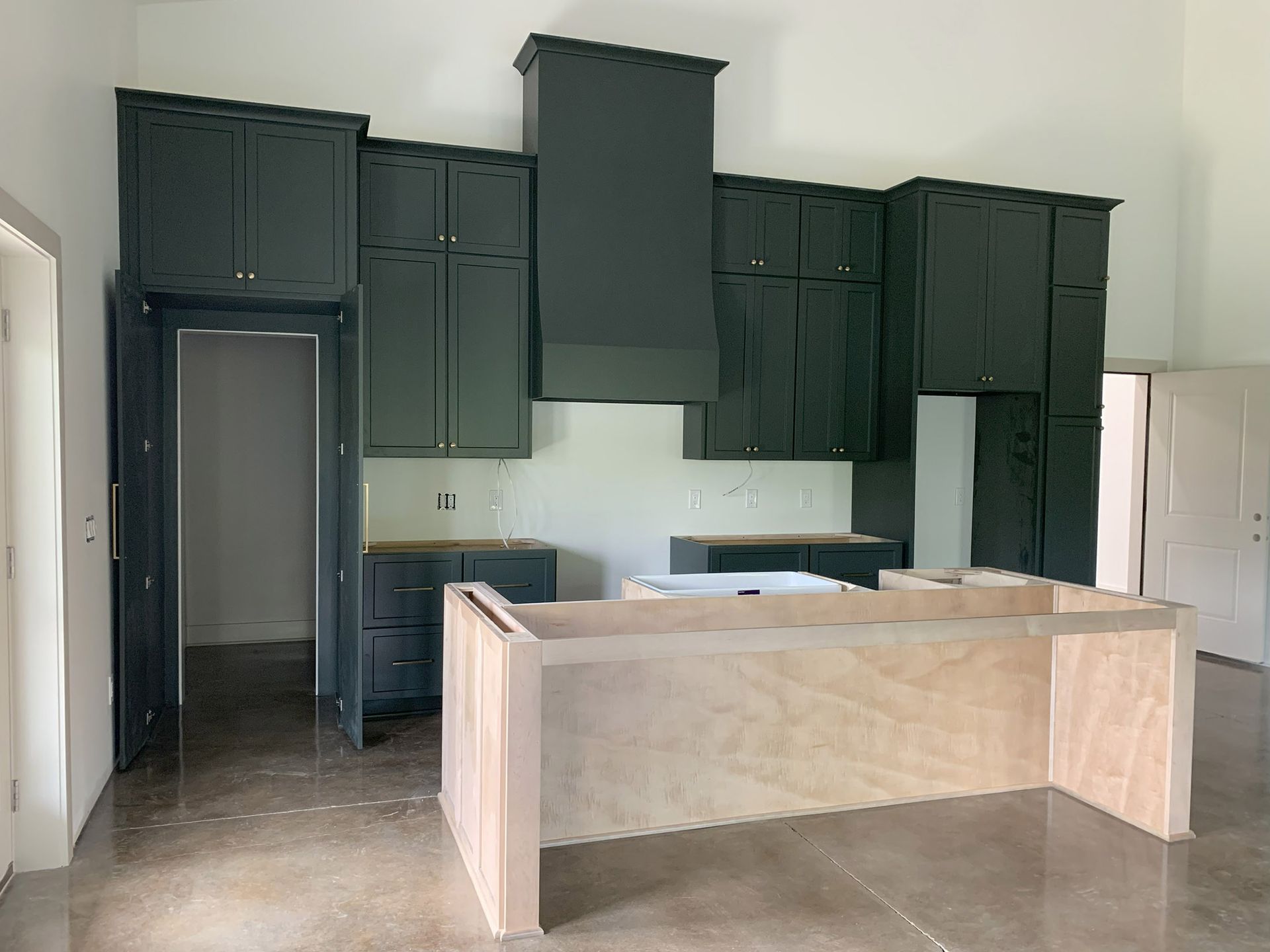 A kitchen with black cabinets and a large island in the middle.