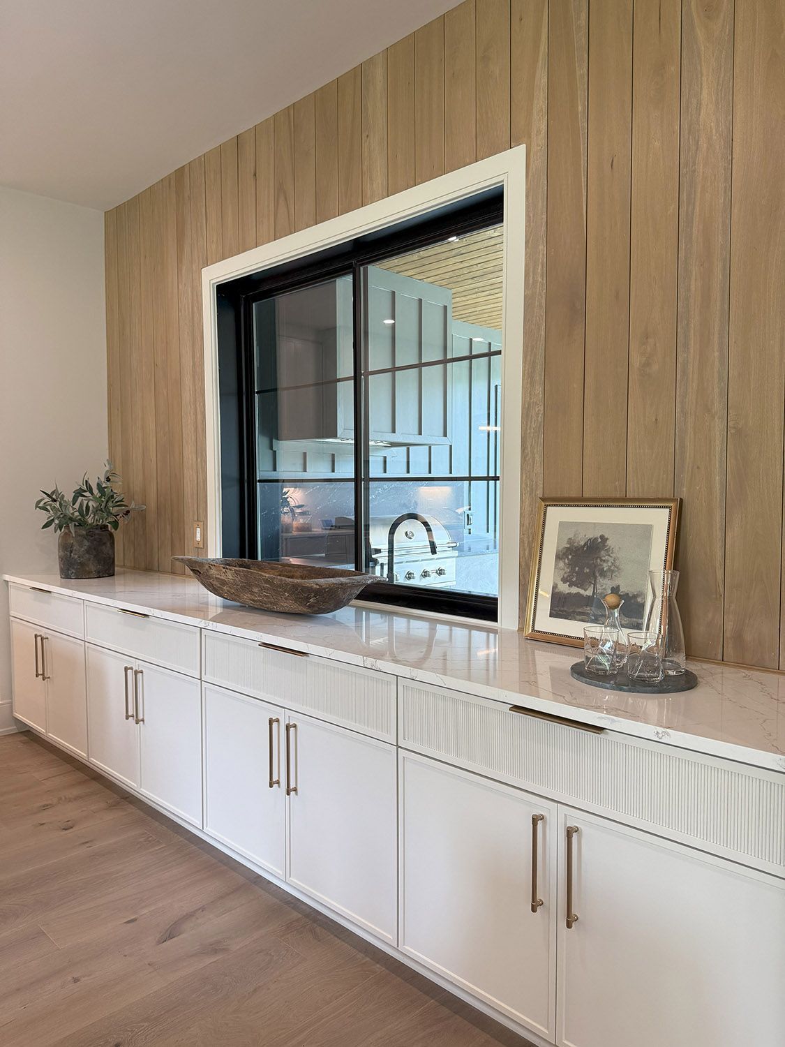 A kitchen with white cabinets and a large window.