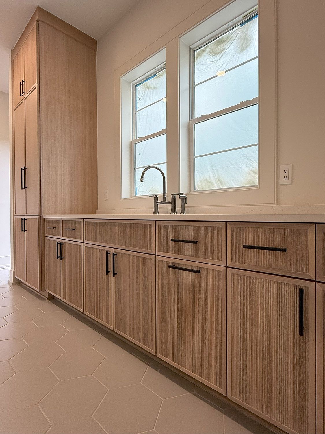 A kitchen with wooden cabinets, a sink, and two windows.