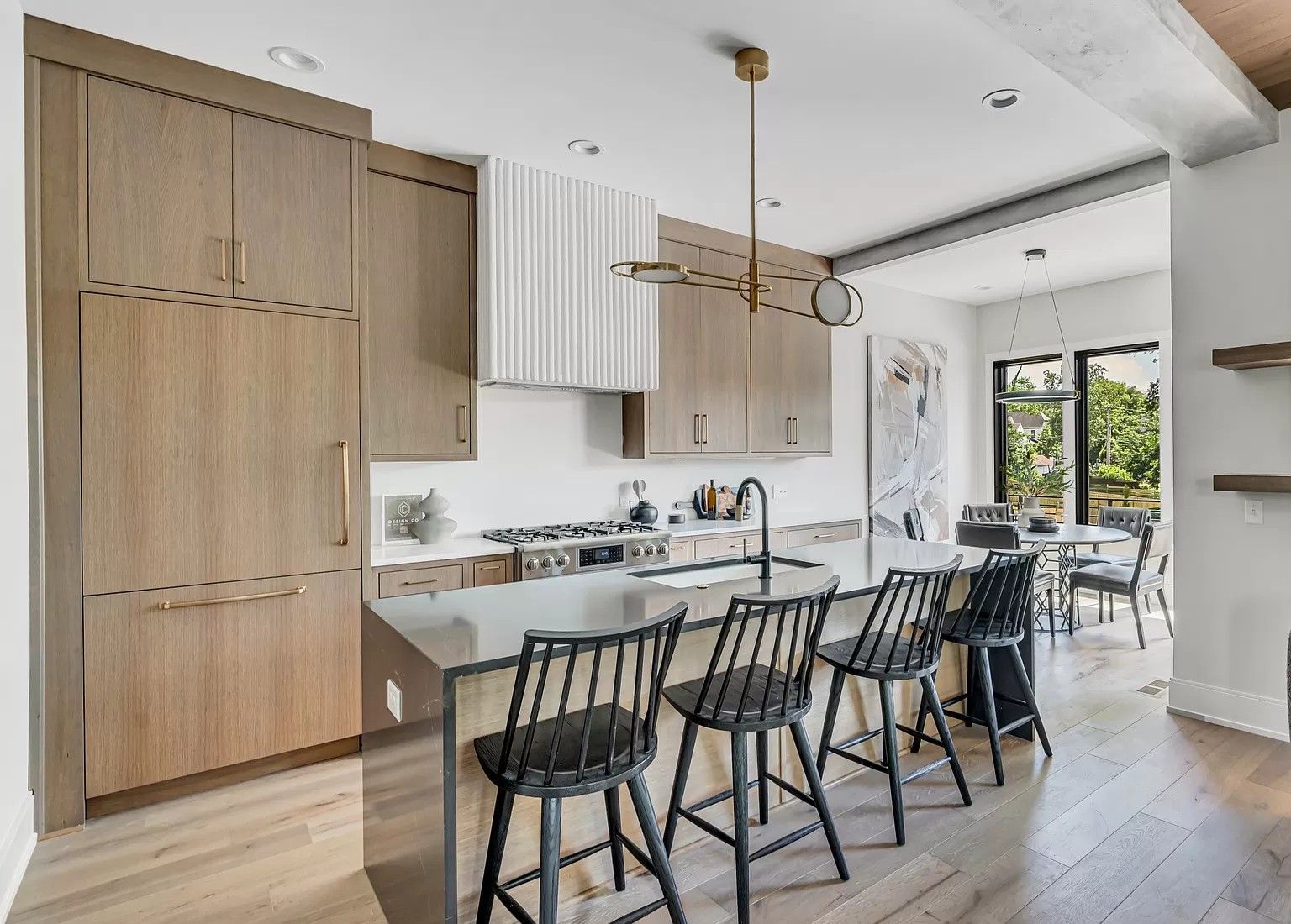 A kitchen with wooden cabinets and stools and a large island.