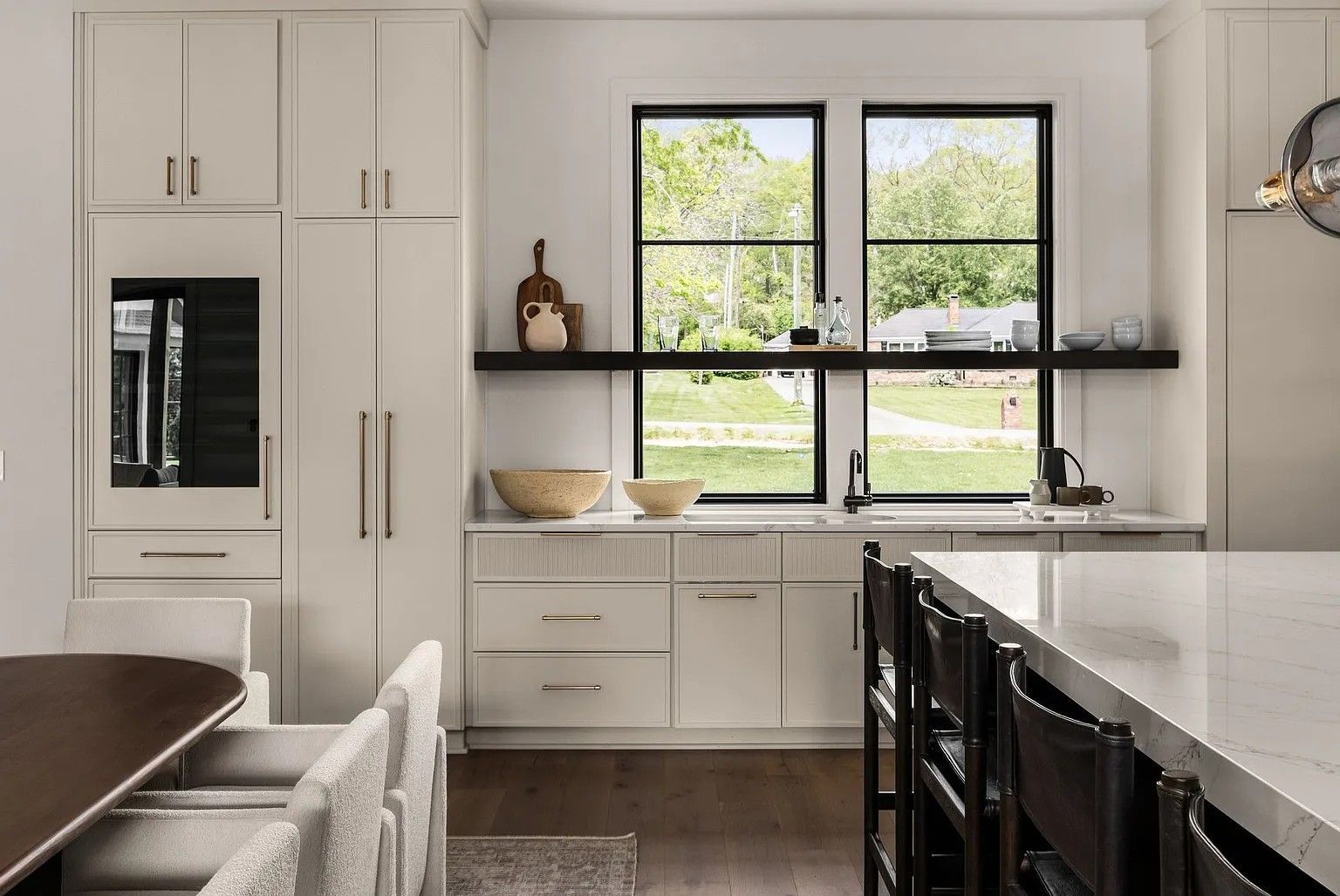 A kitchen with white cabinets, a large island, a table and chairs.