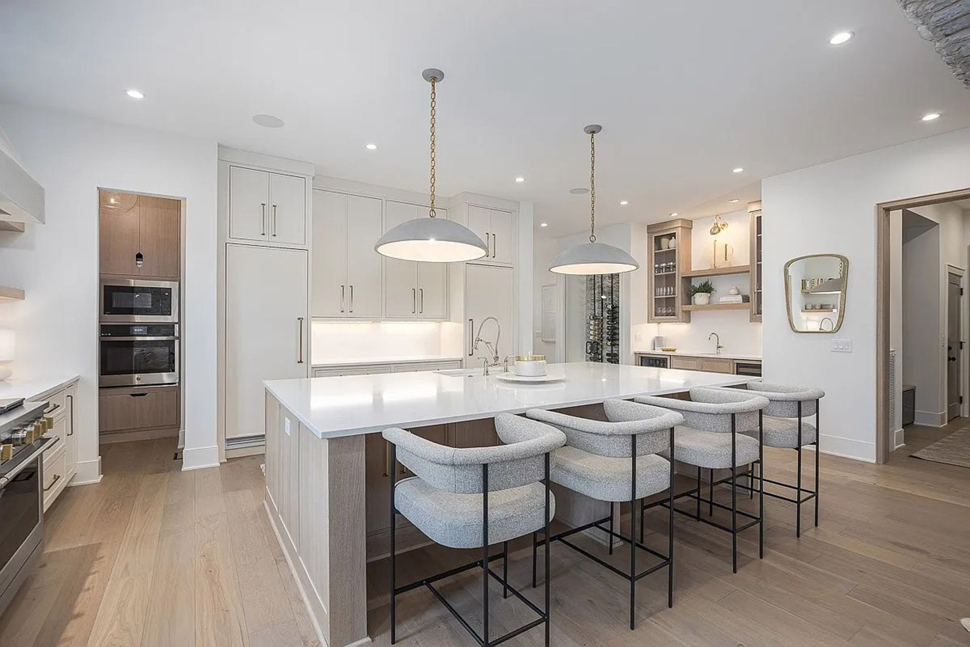 A kitchen with white cabinets, a large island, and stools.