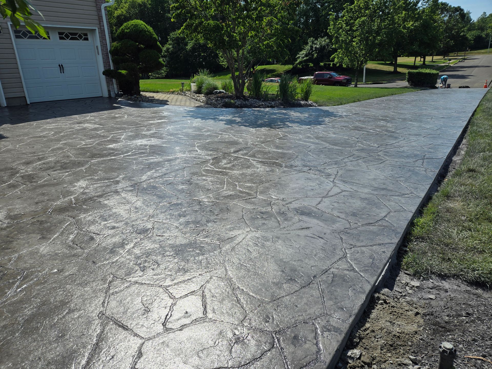 A concrete driveway leading to a garage with trees in the background
