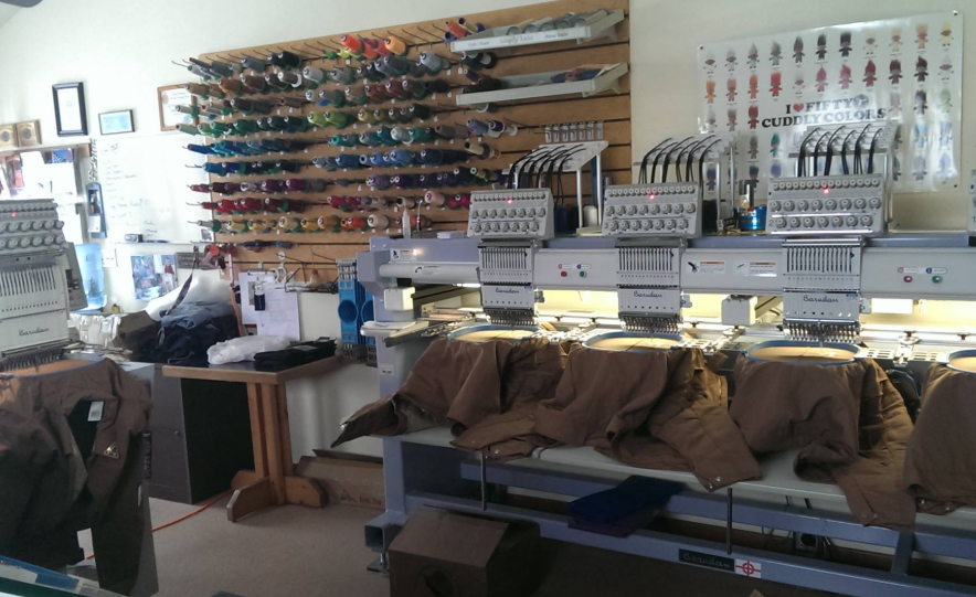 A row of embroidery machines are sitting in a room.