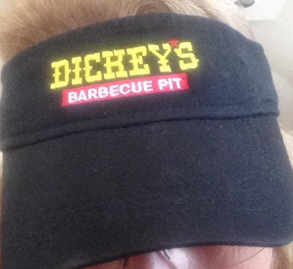 A person is wearing a black hat that says dichey 's barbecue pit