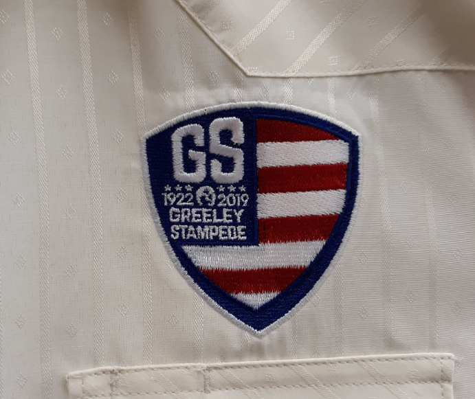 A patch on a white shirt says greeley stampede