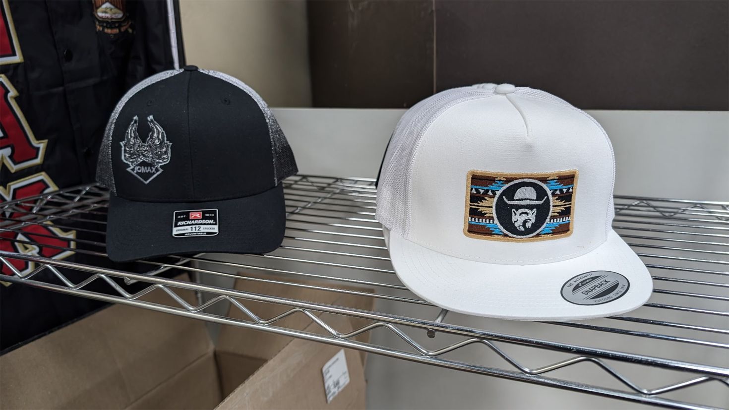 Two hats are sitting on a metal shelf.