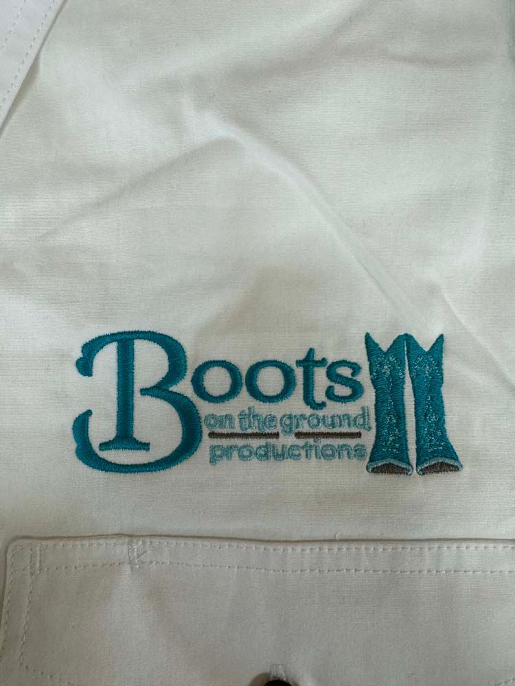 White shirt with embroidered Boots on the Ground Productions text.
