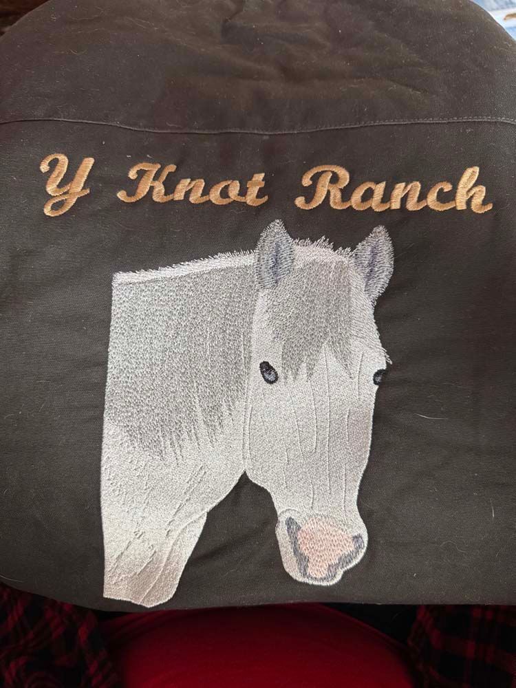 Embroidered design on black fabric with gold lettering.