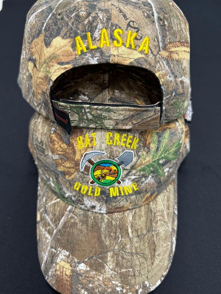Camouflage hats displaying Alaska Hat Creek Gold Mine logo.