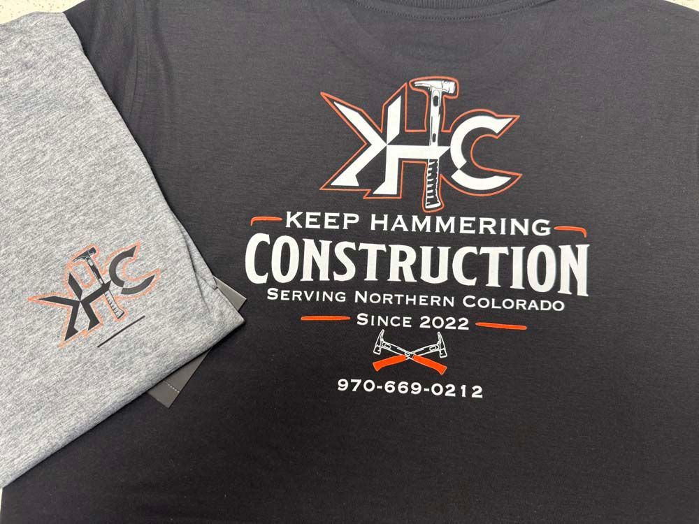 Gray and black t-shirt, with a construction company logo.