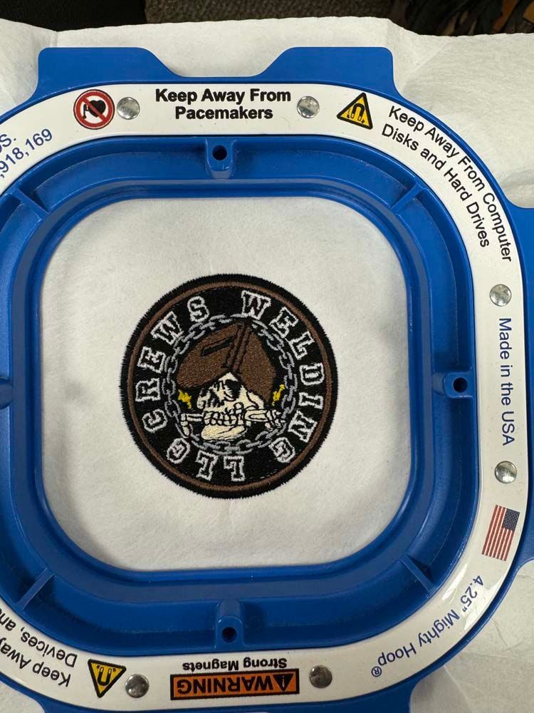 Patch with skull design in embroidery hoop, warning about magnets.