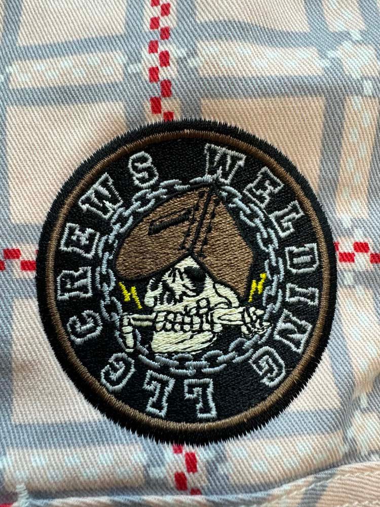 Circular patch, black border, skull welding mask, chains.