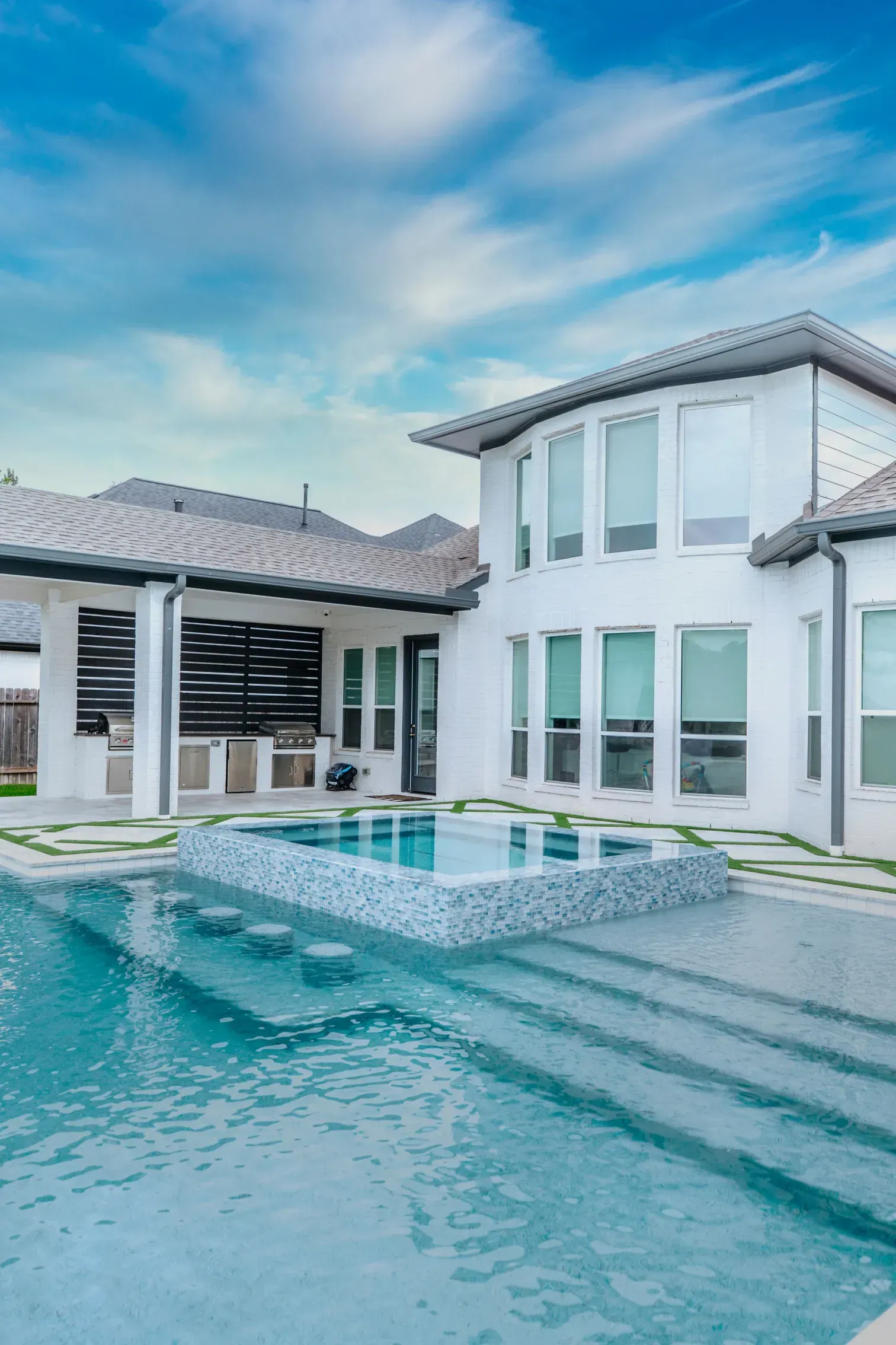 Modern white villa with a turquoise pool and blue sky reflection