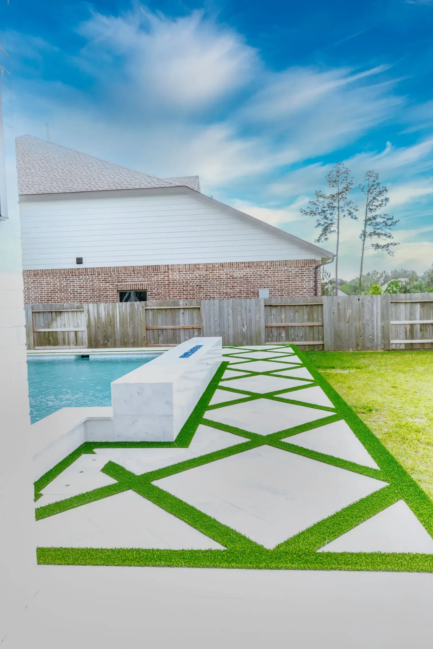 Backyard pool with white lounge chair, green geometric stepping stones, fence, and blue sky