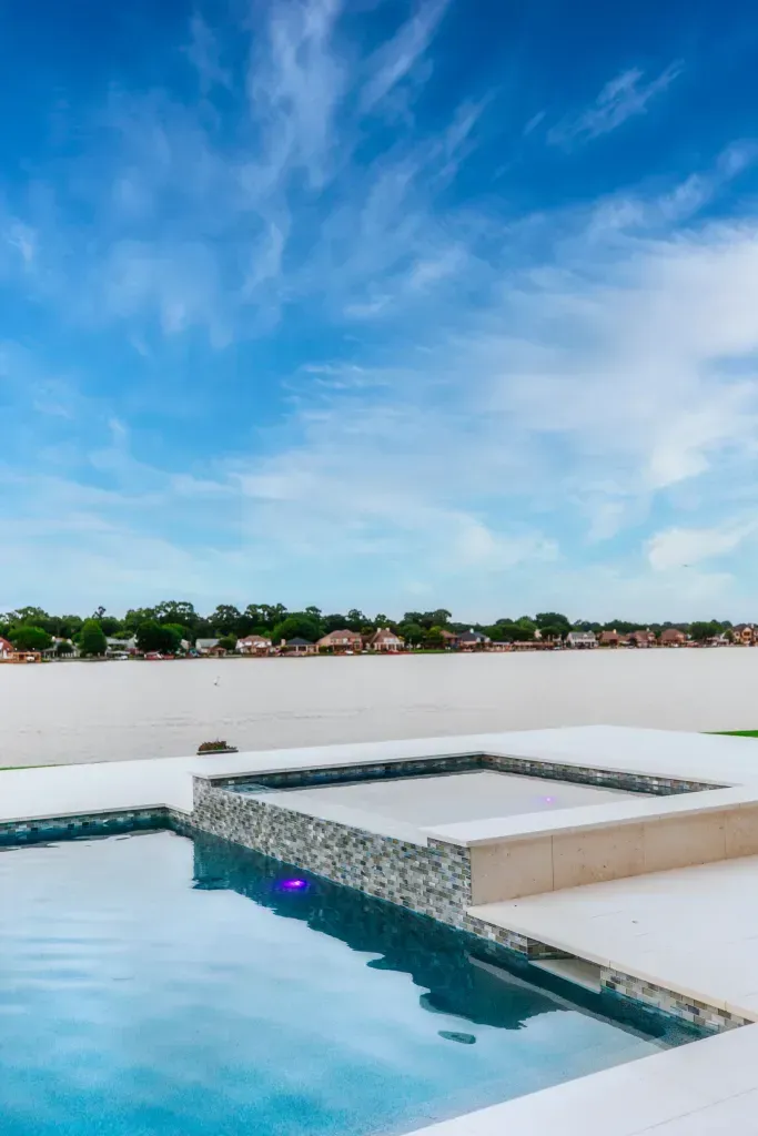 Rooftop pool with blue water and a bright sky above a distant treeline