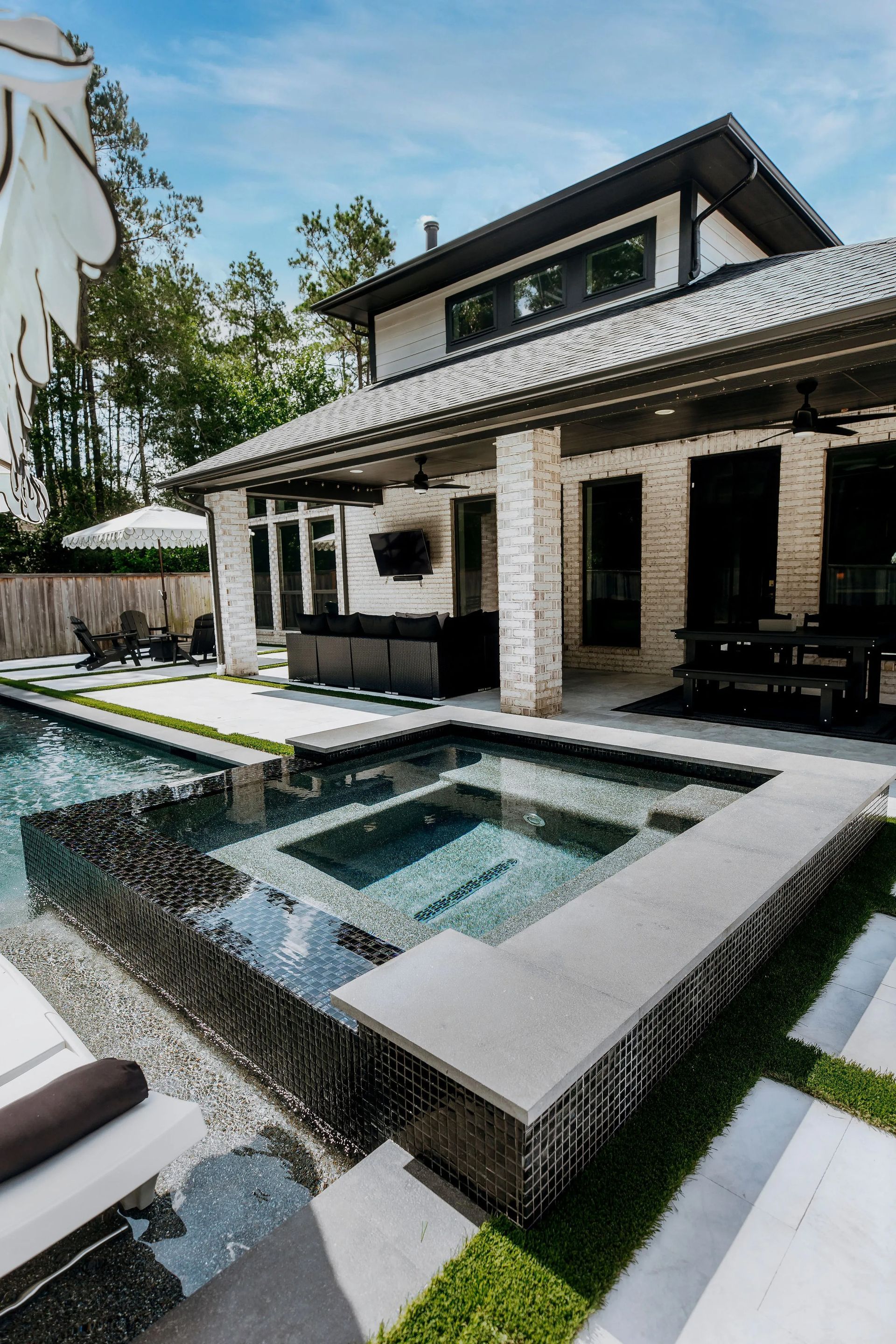 Modern house patio with a small square pool and dark stone trim under a tiled roof