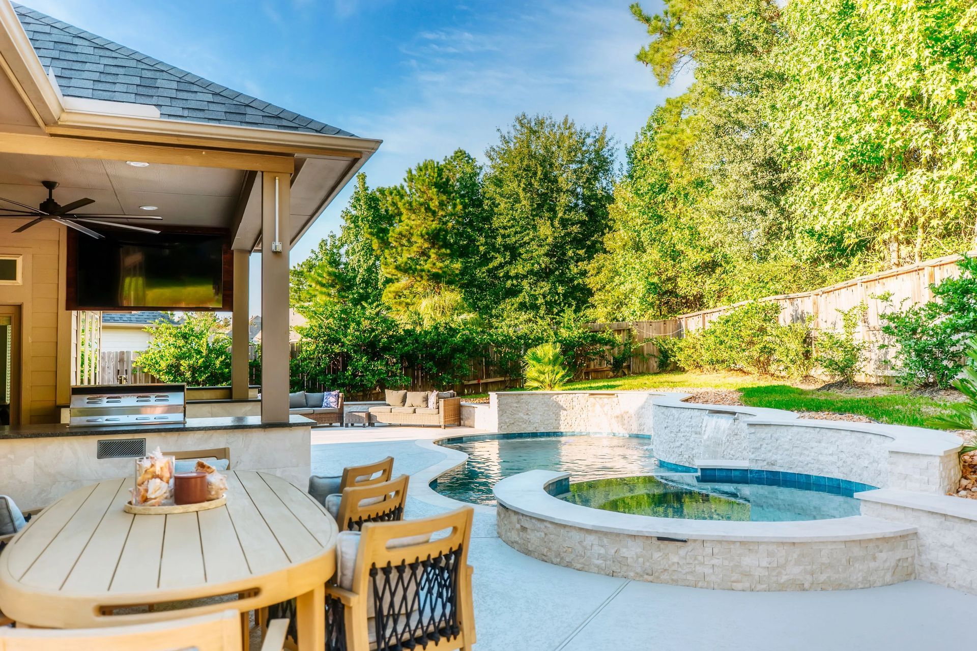 Backyard patio with outdoor dining table, covered seating area, and a round swimming pool with spa