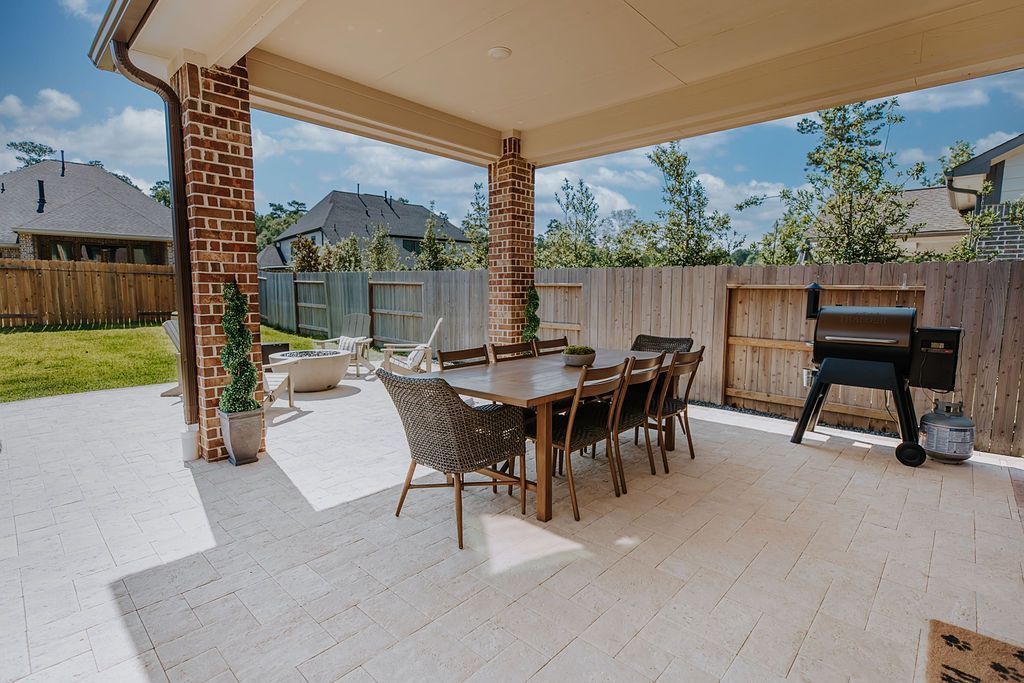 Covered patio with dining table and grill in a fenced backyard