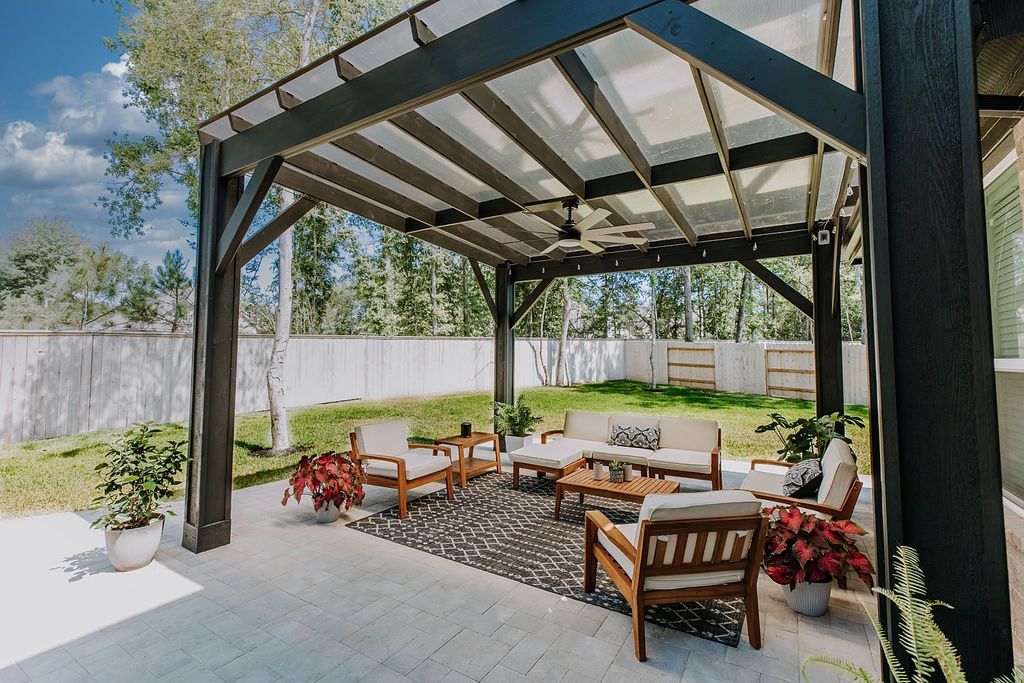Covered patio with outdoor seating, potted plants, and a sunny backyard view