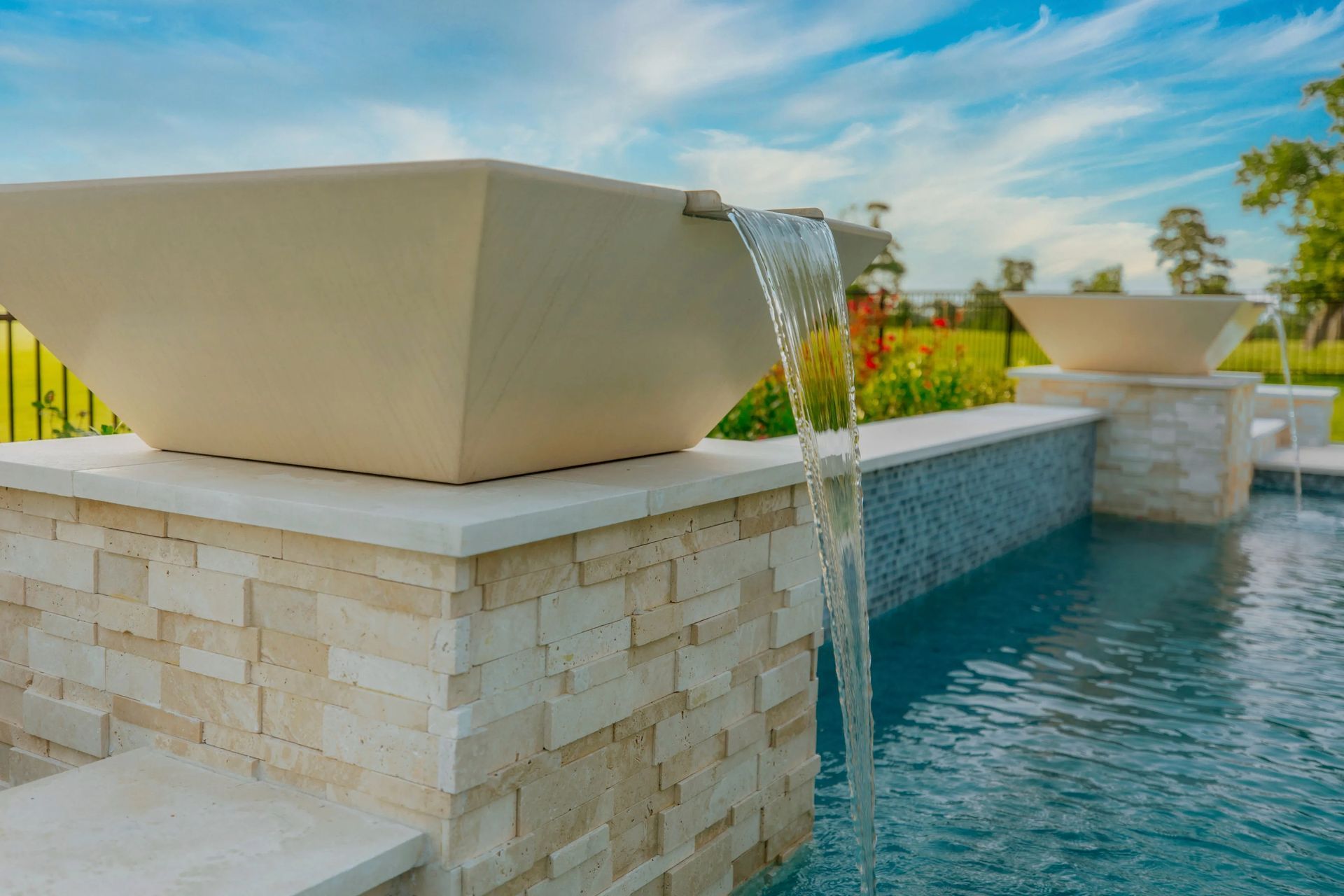 Modern resort pool with stone planters and cascading water features