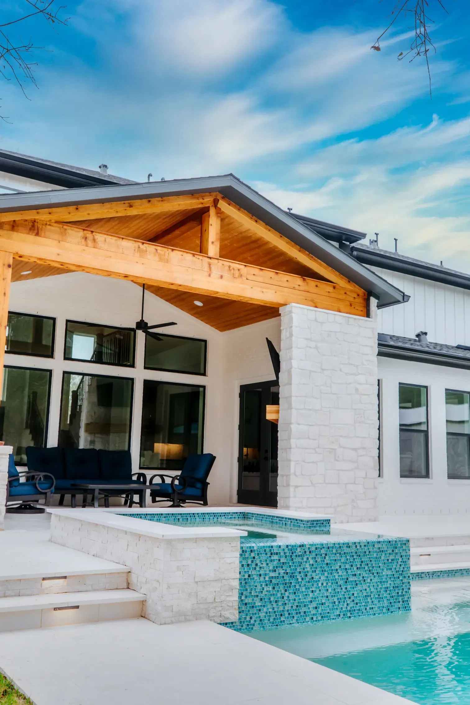 Modern white house with wood patio cover and turquoise pool under a blue sky