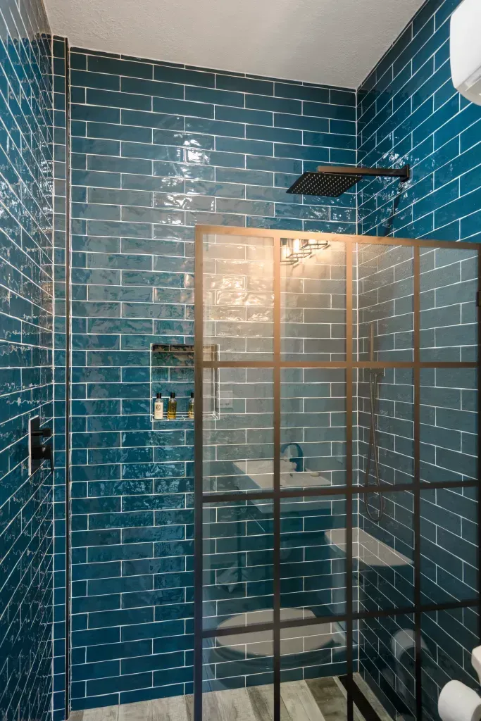 Blue-tiled shower with glass enclosure and warm light reflections