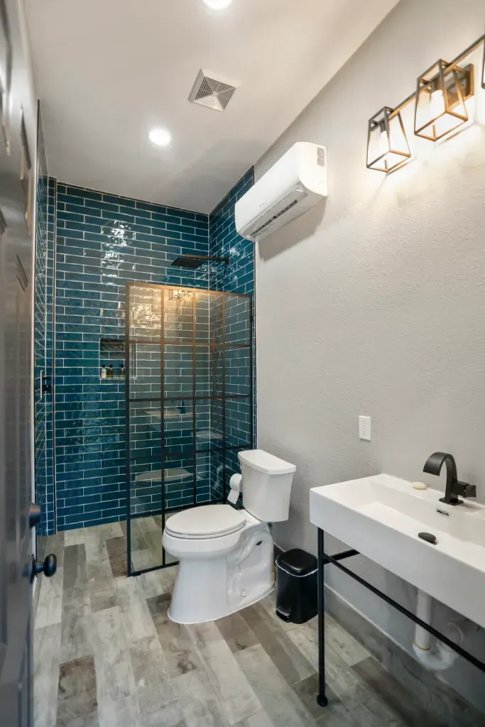 Modern bathroom with glass shower, toilet, and white vanity under wall lights