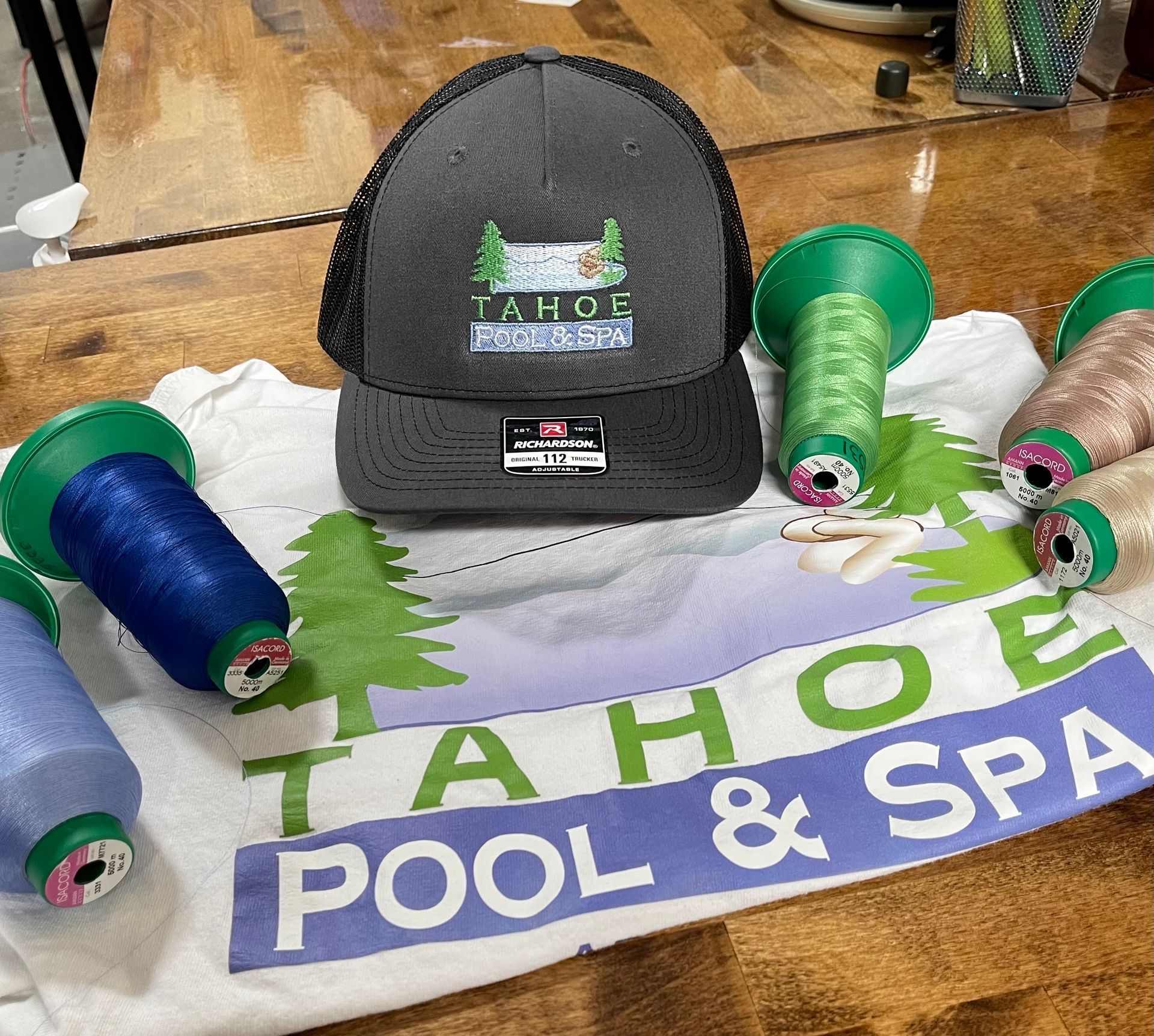 Black cap on towel, surrounded by green and blue pool float toys with “Tahoe Pool & Spa” text.