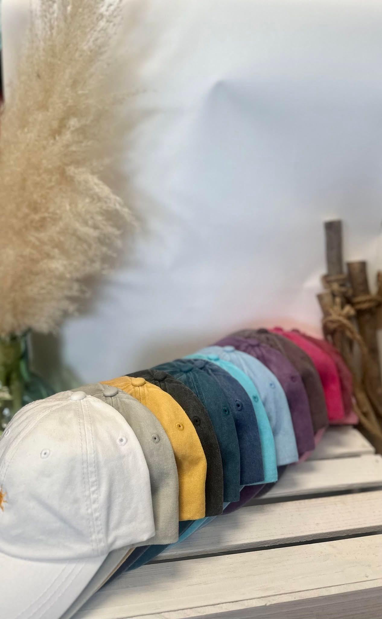 White woven basket with folded, colorful textured headbands on a shelf beside pampas grass.