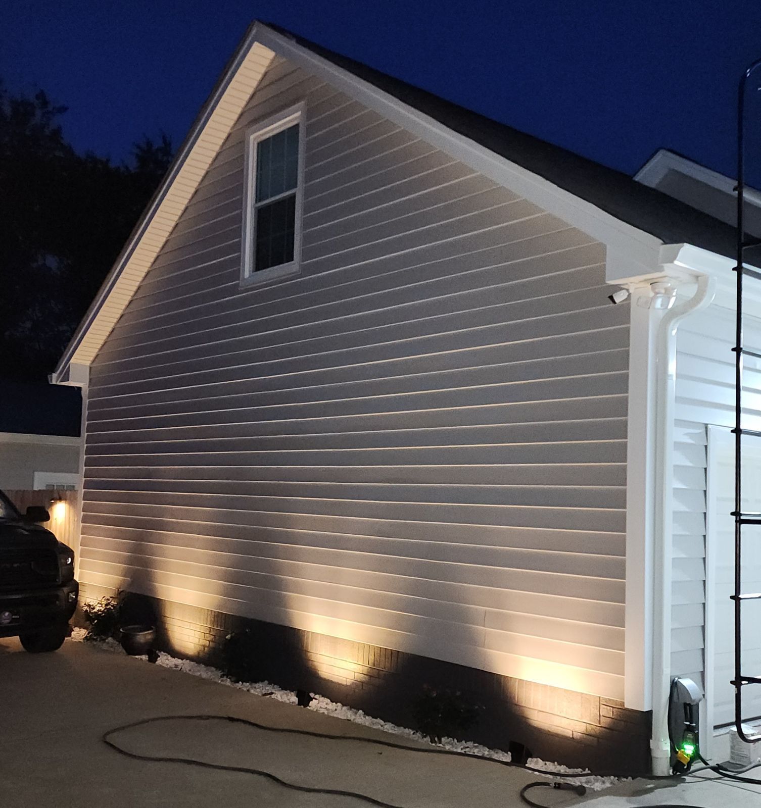 A house is lit up at night with a ladder in the background